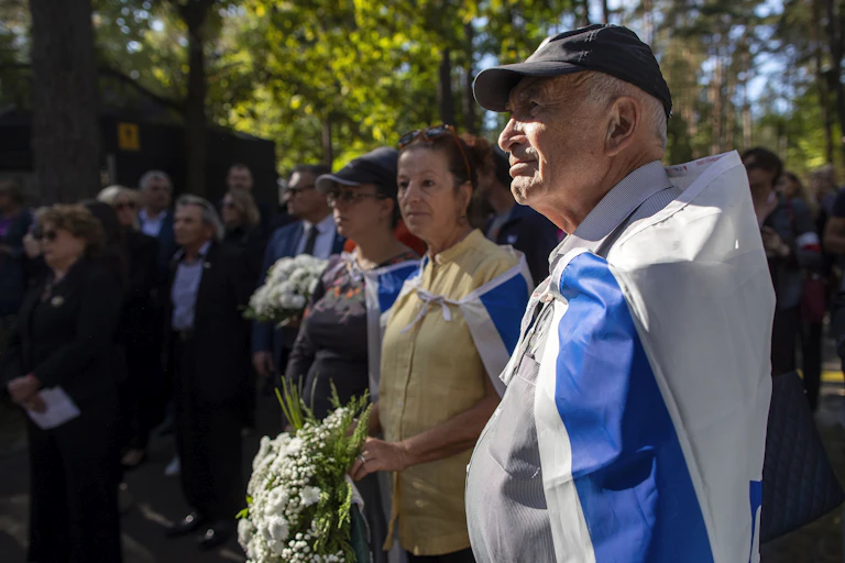 A man listening has an Israeli flag around his shoulders.