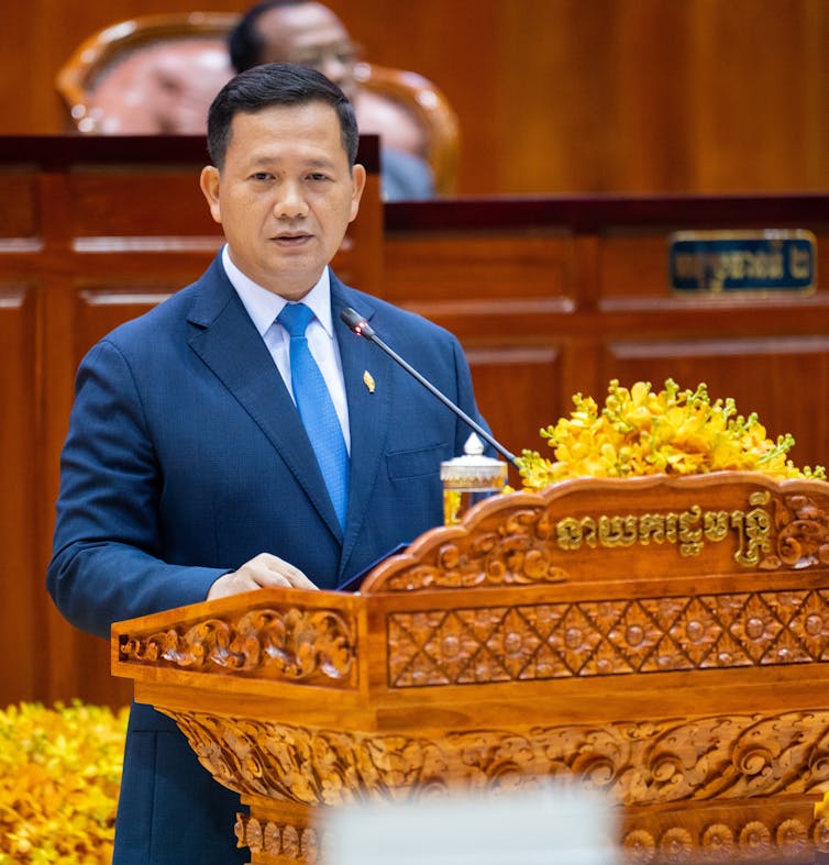 Hun Manet stood at a podium as he delivers a speech.