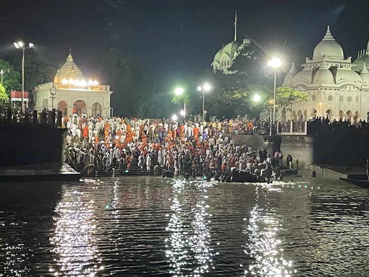 A crowd of people at the edge of a river