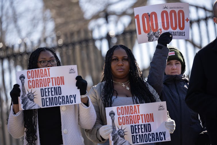 Protesters holds signs that say 'Combat corruption. Defend Democracy'