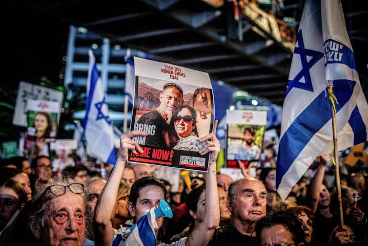 Israeli people hold up pictures of hostages.