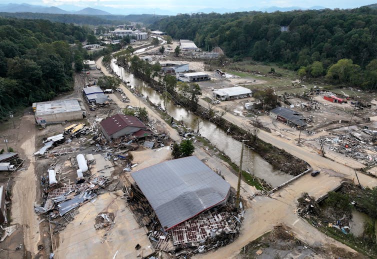 Buildings are torn apart and debris is strewn everywhere along one of Asheville's rivers, the Swannanoa.