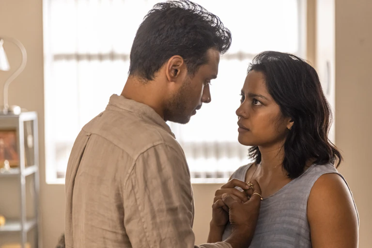 An South-Asian couple gaze at one another while touching hands.