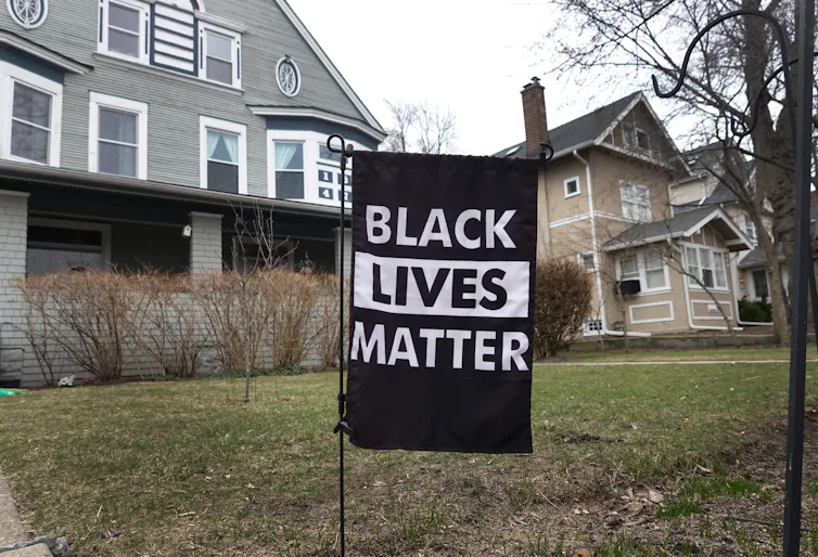 A 'Black Lives Matter' sign sits on a lawn in front of a stately house