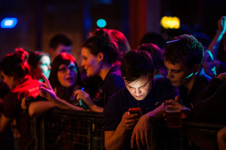 Young man checking his phone at a concert