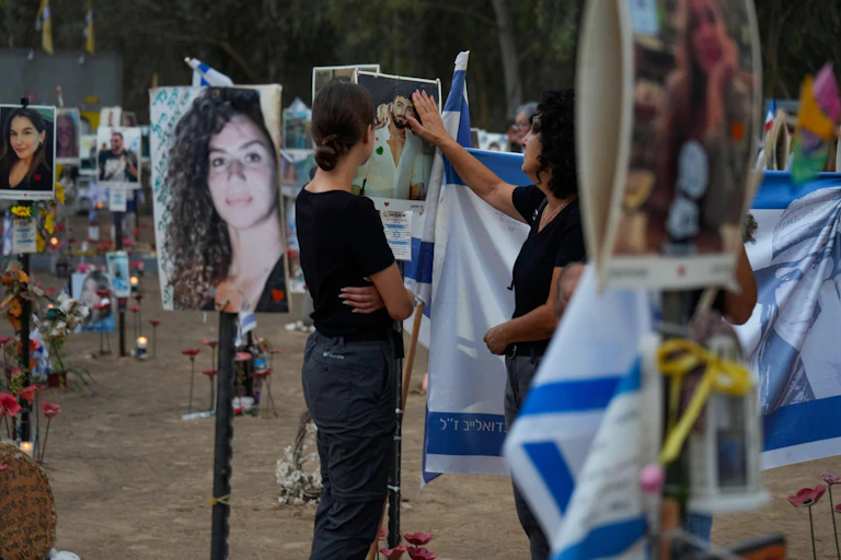 People look at and touch pictures of victims of the October 7 atttack.