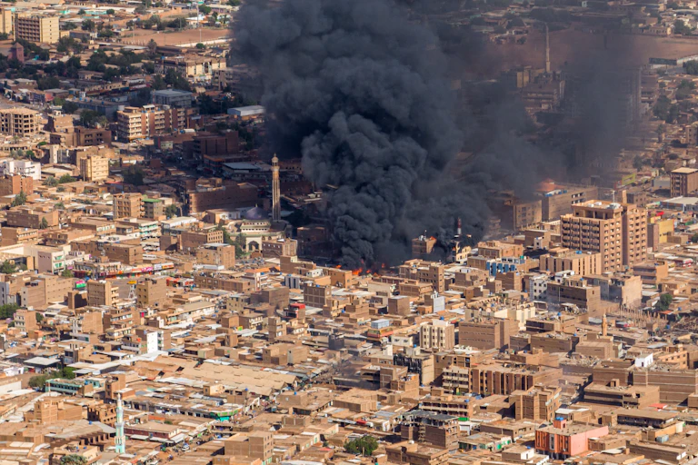 A huge cloud of black smoke rises from a city.