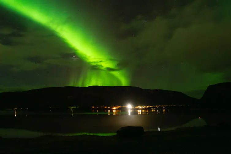 A blaze of neon green lights up the night sky, which is a slightly darker shade of green