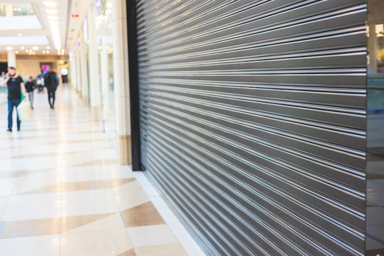 A storefront is closed with a metal shutter.