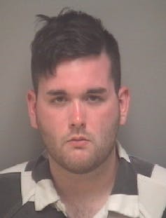 An image of a white man staring into a camera at a police station.
