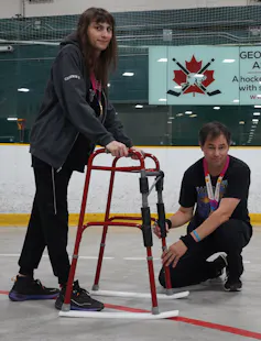 Two people standing with an assistive device on ice.