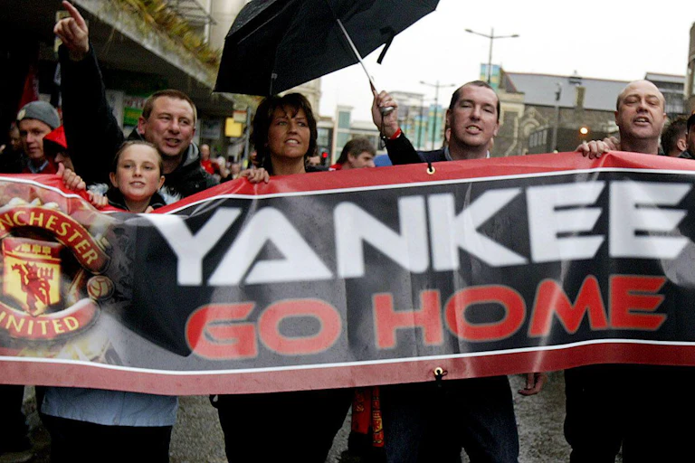 Manchester United fans holding a banner telling new American owner Malcolm Glazer to 'go home'.