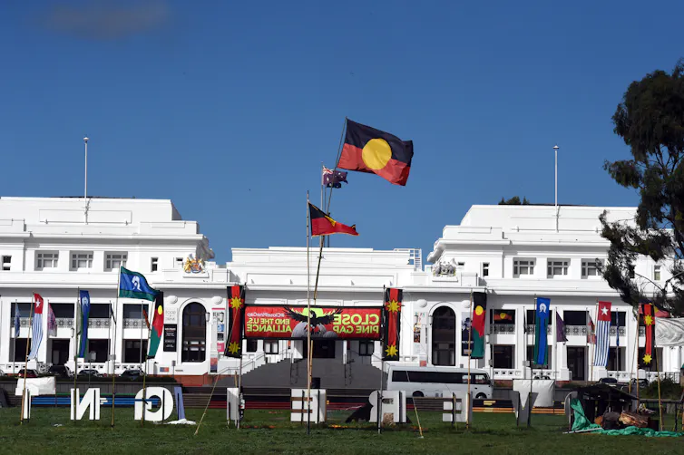 A large white building with Aboriginal flags flying out the front.