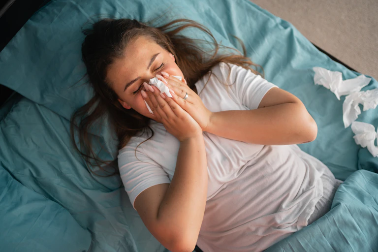 Woman blows her nose in bed