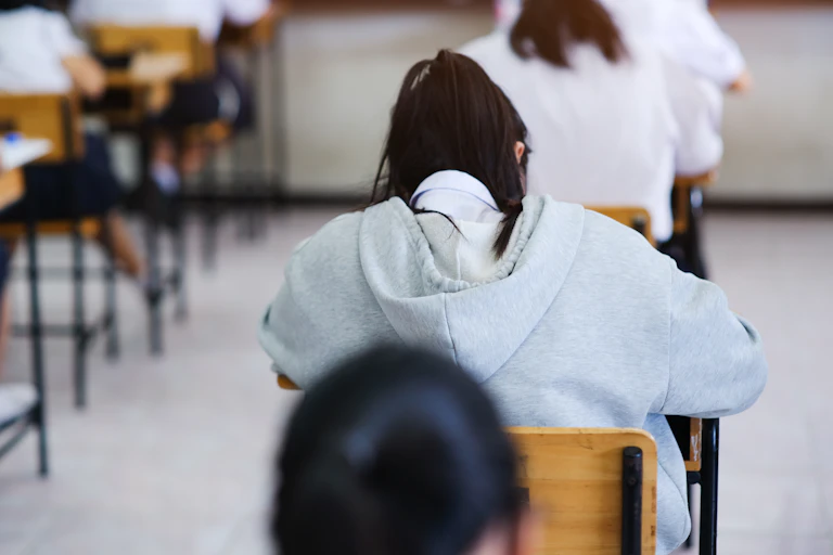 Students lean over desks, writing.