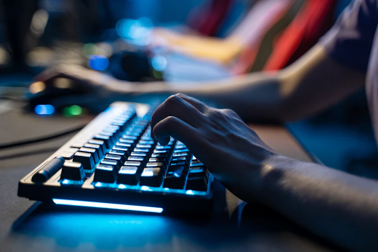 Human hand typing on keyboard in dark room.