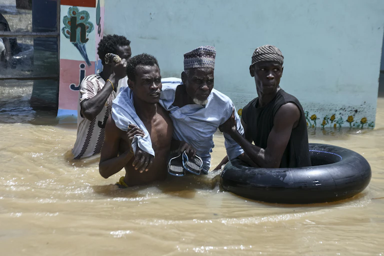 Men wading through waist-level flood waters