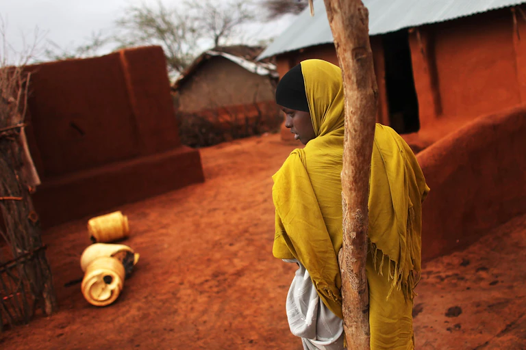 A woman leans against a tree