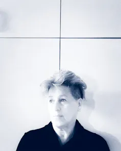 A black and white image showing a person at the bottom of the shot dressed in a black shirt with short wavy hair.