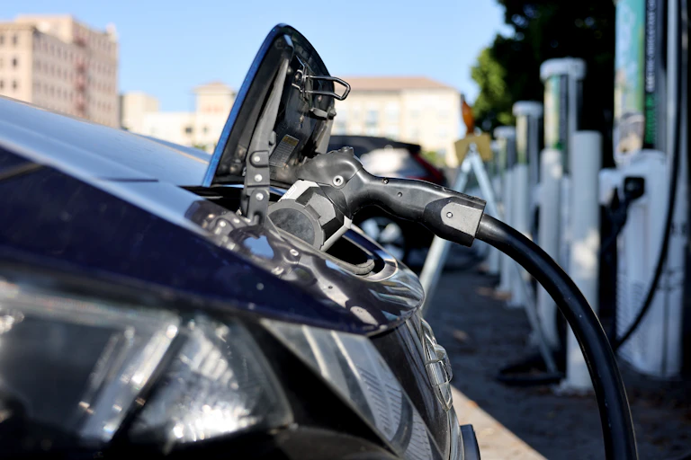 An EV plugged in at a row of outdoor chargers