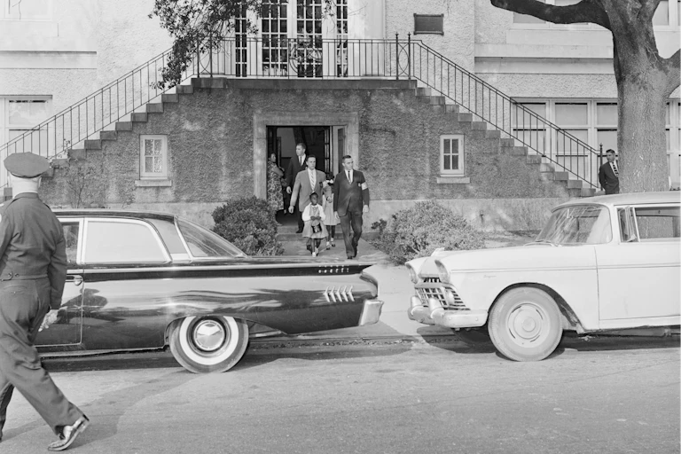 Three little Black girls leaving a school building accompanied by federal marshals