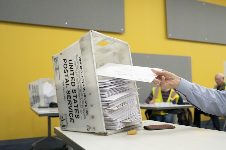 A person places an envelope on a stack of other envelopes.