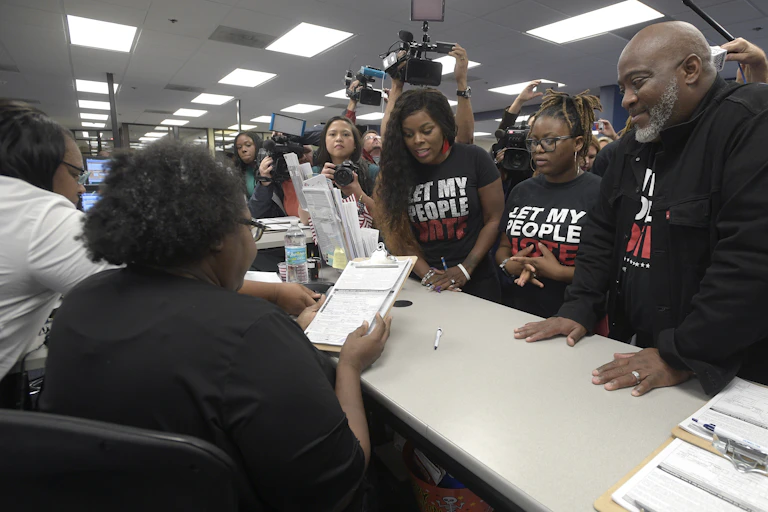 A Black man is surrounded by his family as he registers to vote.