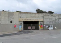 Vehicle entrance to a low-slung concrete building marked 'Oceanside Water Pollution Control Plant'