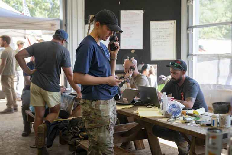 People in matching navy t-shirts handle logistical work in a field office.