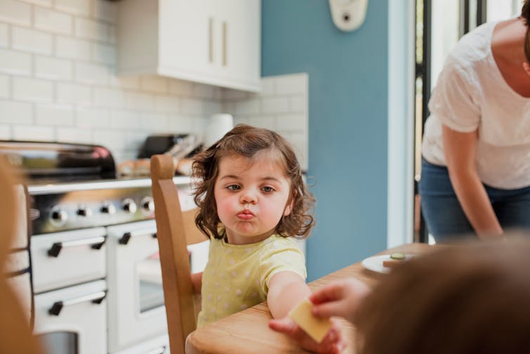 A small child is handed a little treat by her parent.