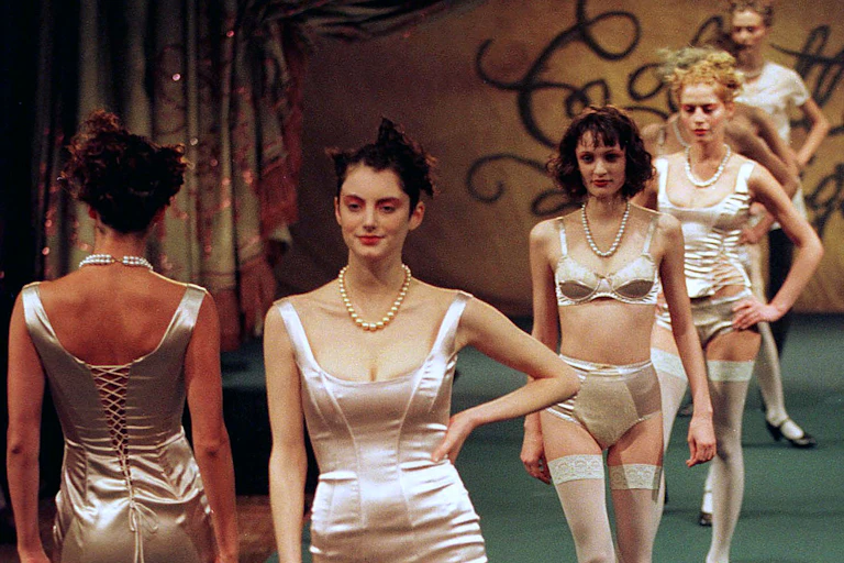 fashion models walk in a line wearing pale pink silk and satin dresses and underwear