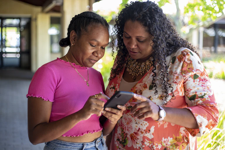 Two Aboriginal women look at a smartphone