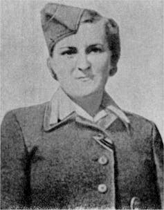 An old black and white photograph of a female concentration camp guard in uniform.