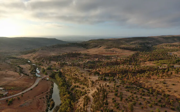 An aerial view of a mountainous area with a river running through it and many trees on the hills.