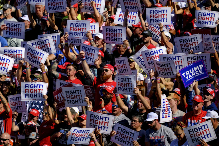 A crowd of people hold up signs urging supports of Donald Trump to fight, fight, fight.