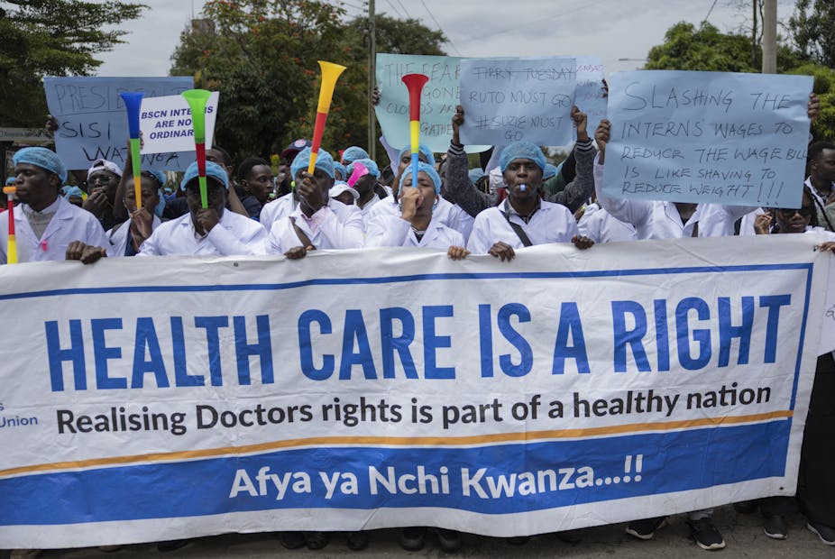 A crowd of people blowing vuvuzelas and holding up a placard written 'Healthcare is a right'