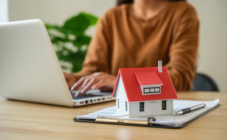 The Quiet Revolution In New Zealand'S Property Valuation: Ai, Transparency, And Trust 4 Woman on laptop with a clipboard and small model house in foreground