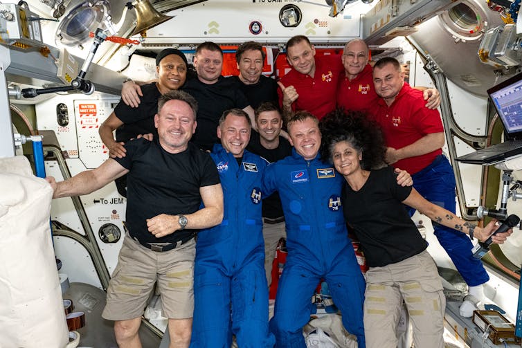 A group of people in red, black and blue outfits smile for the camera.