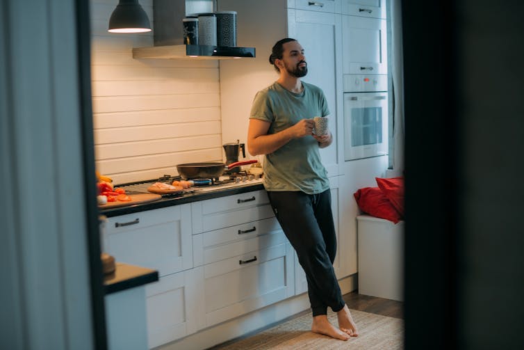 Man stands in kitchen drinking coffee