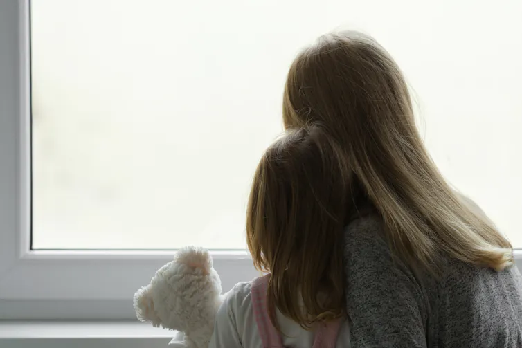 Mother and child facing away looking out a window.