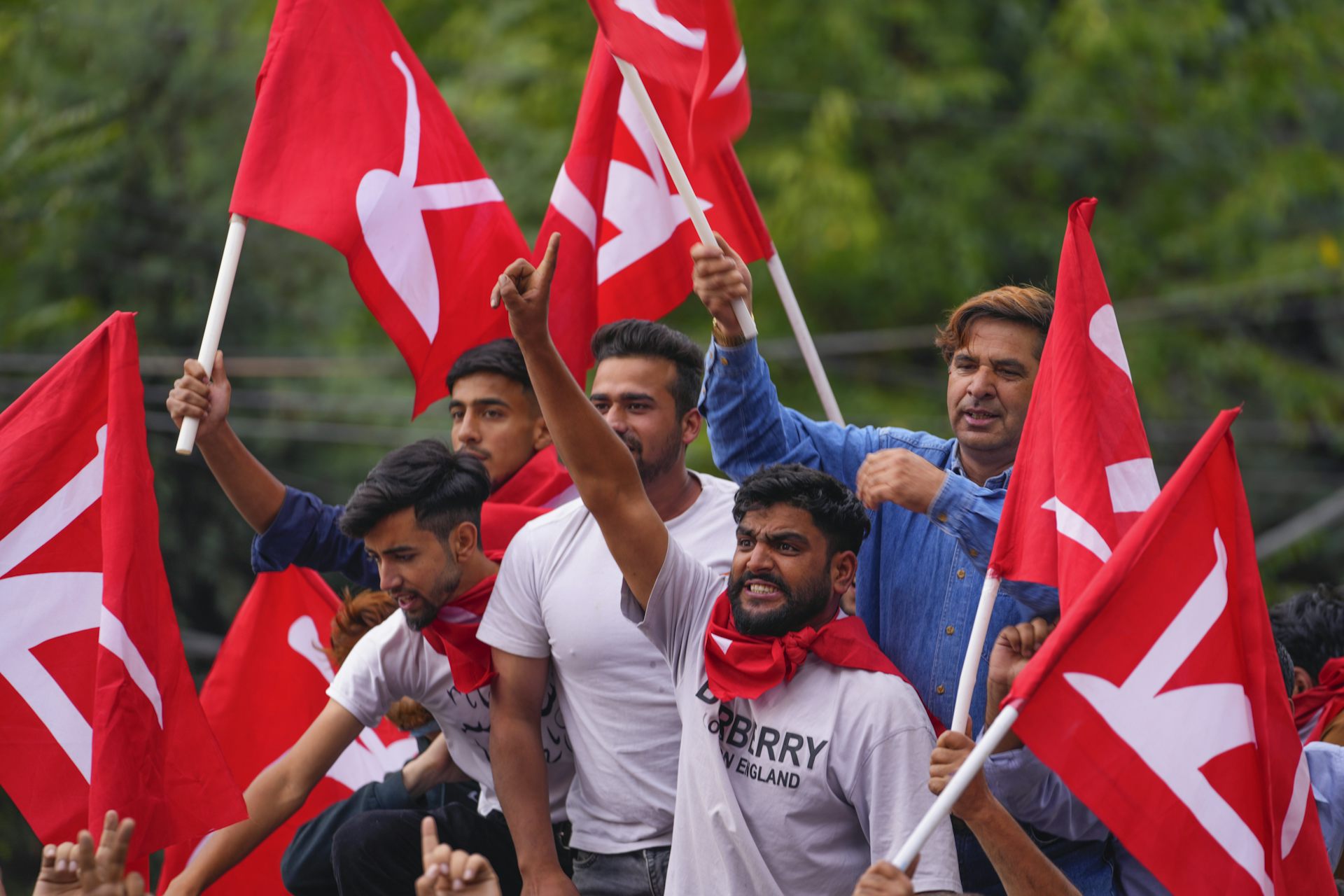 Men waving red flags celebrating in a truck.