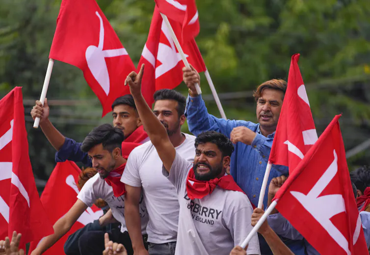 Men waving red flags celebrating in a truck.