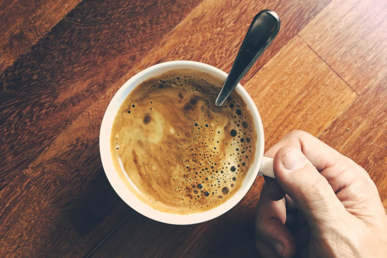 Person hold coffee cup after stirring in cinnamon