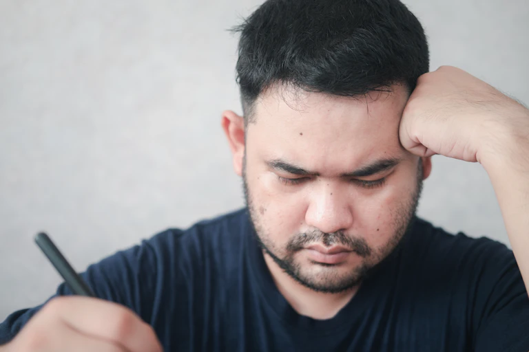 Man holding pen and frowning