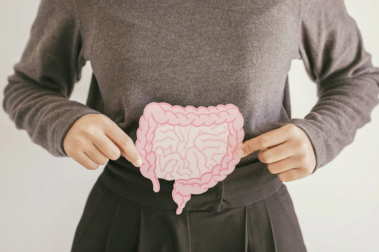 A woman holding a cardboard cutout of human intestines over her stomach area.