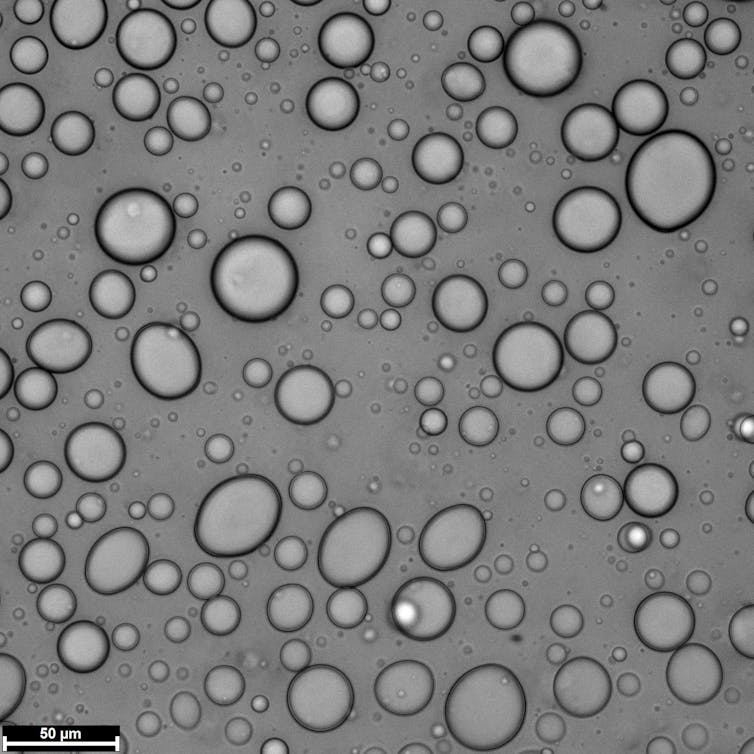 Small opaque spheres resembling droplets against a grey background