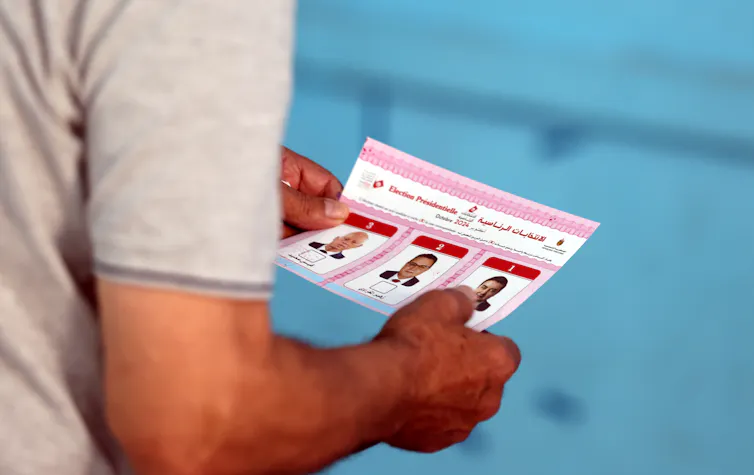 A Tunisian man holds a ballot at a polling station.