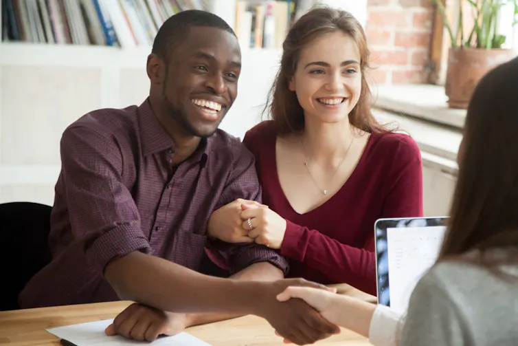 couple in a meeting with a woman, man shaking her hand