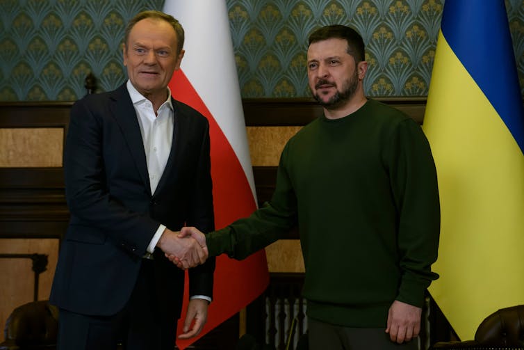 Poland's prime minister shakes hands with Ukraine's president in front of both countries' flags
