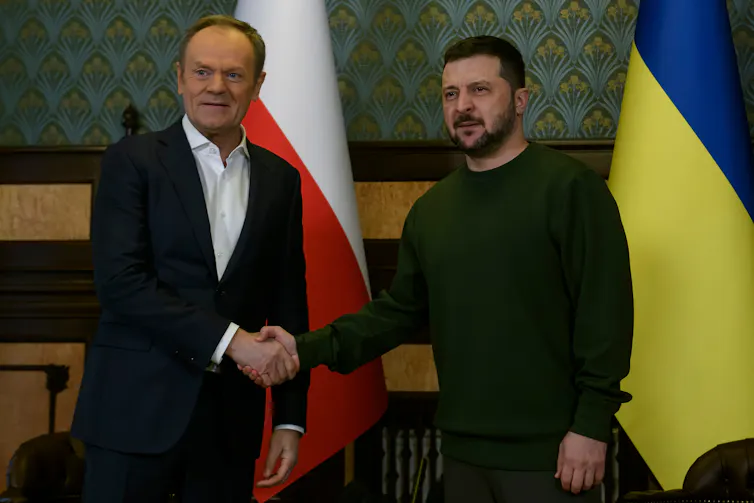Le premier ministre de la Pologne serre la main au président de l’UKraine devant les drapeaux des deux pays